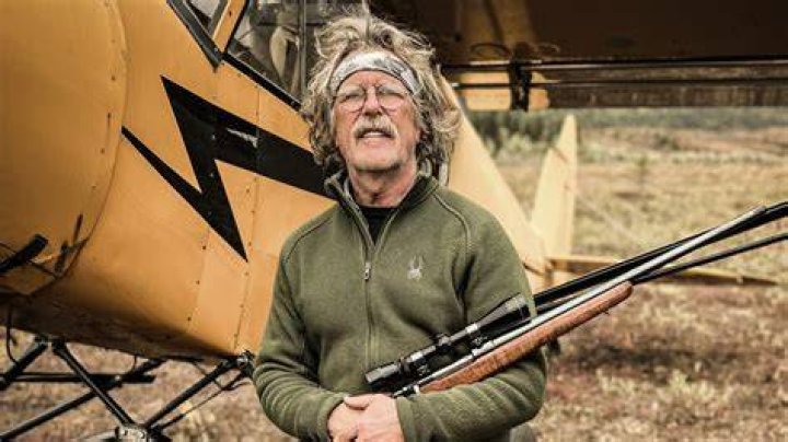 Marty Meierotto in a dark brown jacket and black pants looking through binoculars.